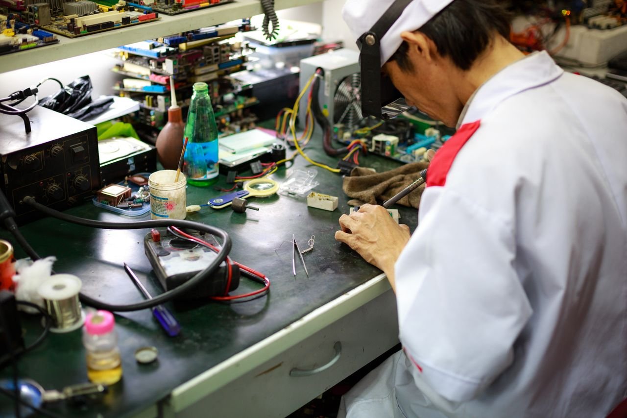 Mastering the First Impression: Your intriguing post title goes here A skilled technician focuses on repairing electronic components at a busy workbench.
