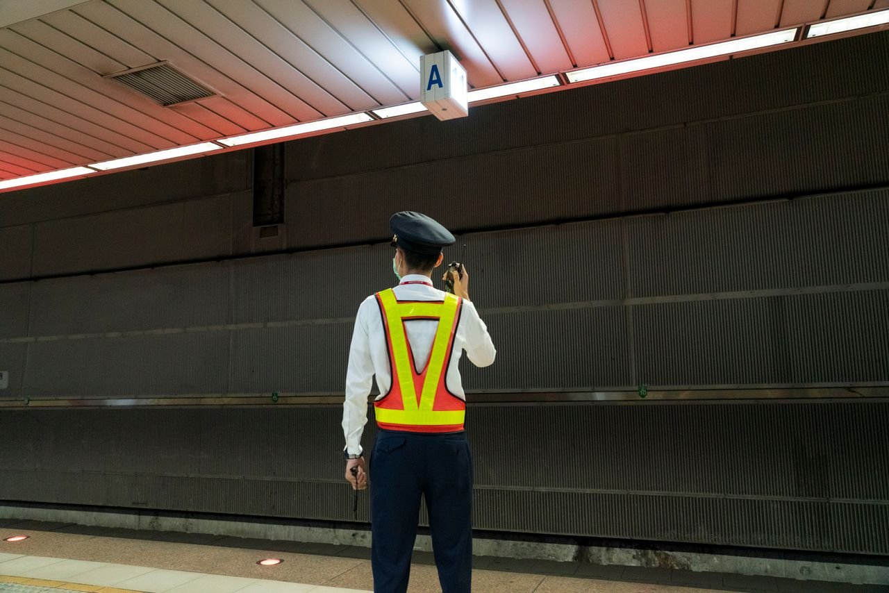 A security guard communicates via radio in an empty train station.